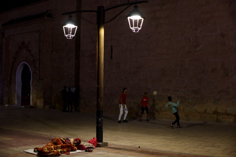 &copy; Reuters. People play soccer next to a woman resting on the sidewalk in Marrakesh, following a powerful earthquake in Morocco, September 9, 2023. REUTERS/Hannah McKay 