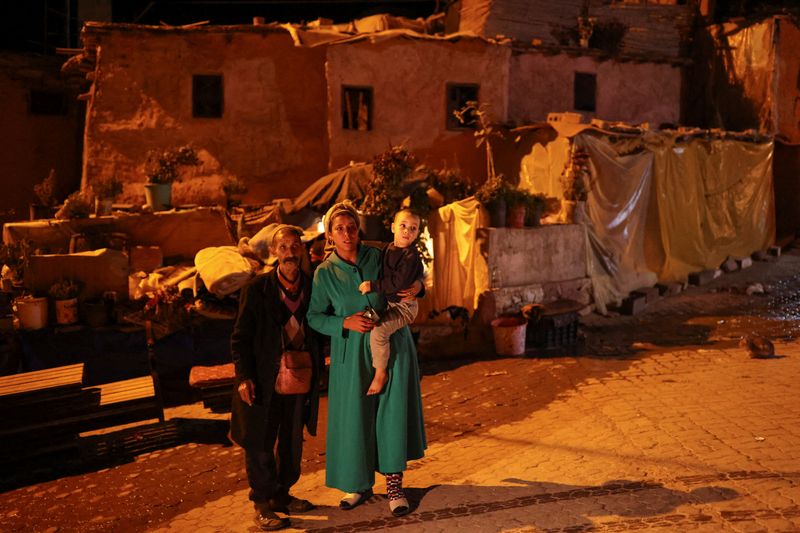 &copy; Reuters. عائلة مغربية تقف بجانب منزلهم المدمر عقب زلزال ضرب المغرب يوم السبت. تصوير: ناتشو دوس - رويترز.