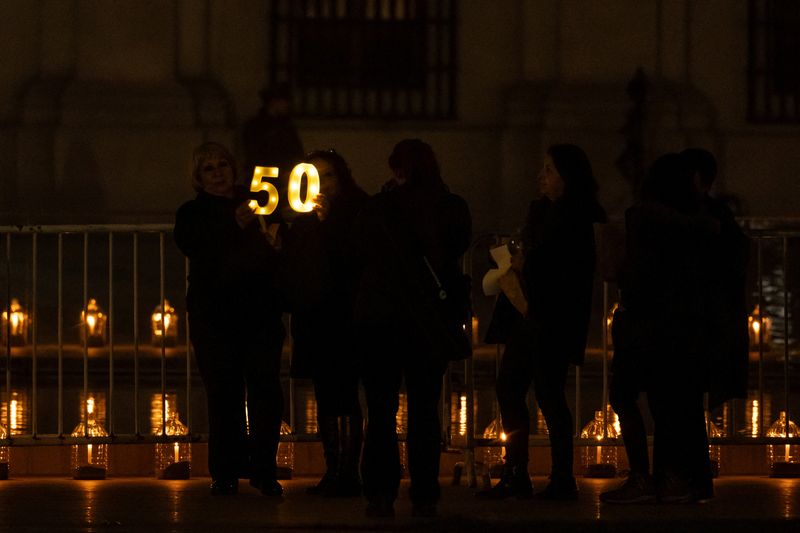 &copy; Reuters. Mulher vestida de preto segura sinal luminoso com o número 50 em torno do palácio presidencial de La Moneda, em Santiago, no Chile
11/09/2023 REUTERS/Carlos Barria