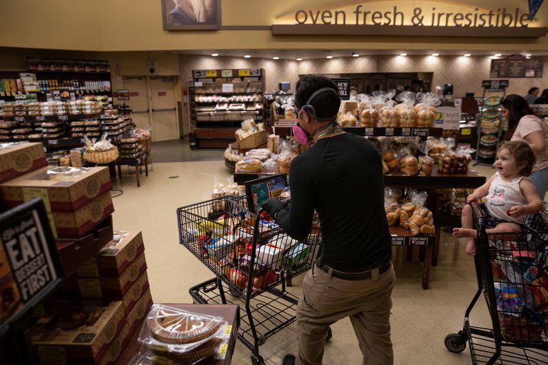 © Reuters. Instacart employee Eric Cohn, 34, navigates a Safeway grocery store while preparing a delivery order while wearing a respirator mask to help protect himself and slow the spread of the coronavirus disease (COVID-19) in Tucson, Arizona, U.S., April 4, 2020.  REUTERS/Cheney Orr