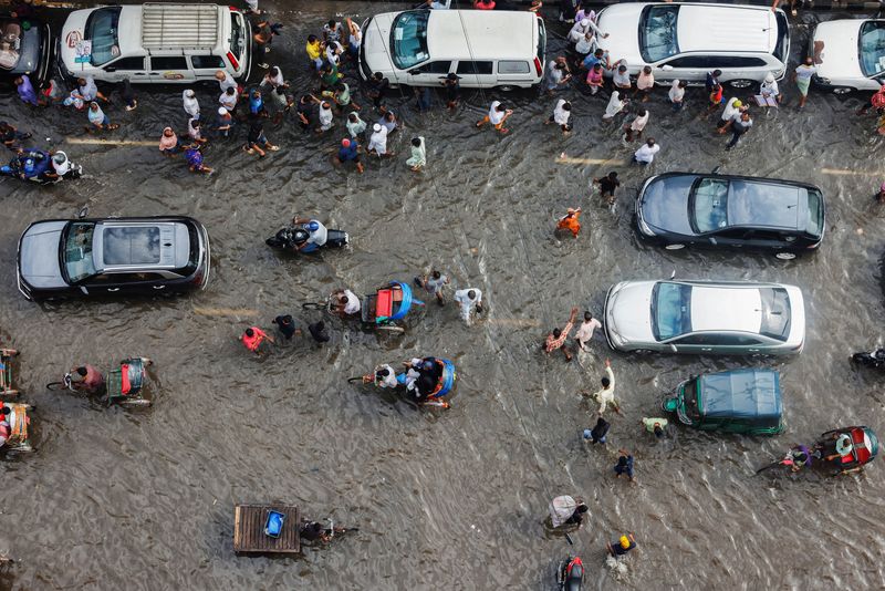 &copy; Reuters. FILE PHOTO: Commuters and vehicles move on a flooded street after rain in Dhaka, Bangladesh, August 4, 2023. REUTERS/Mohammad Ponir Hossain/File Photo