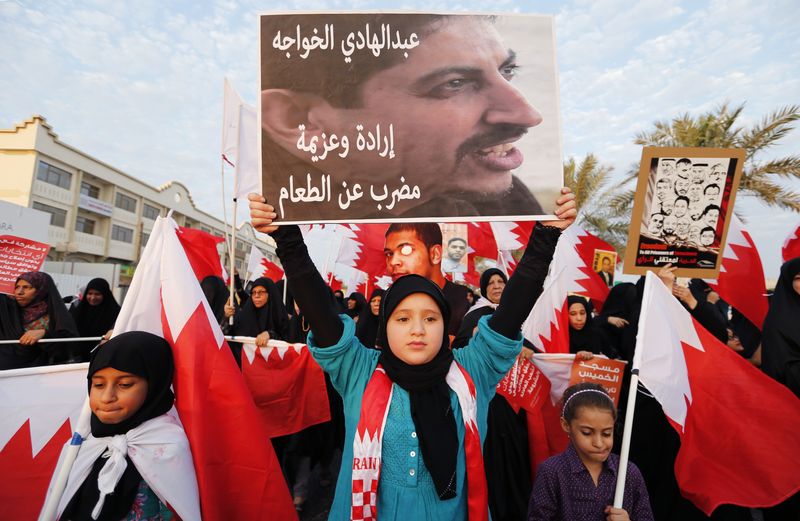 © Reuters. متظاهرة تحمل صورة الناشط الحقوقي البحريني البارز عبد الهادي الخواجة (في المنتصف) في البديع غربي المنامة بصورة من أرشيف رويترز.