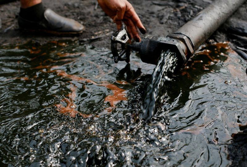 &copy; Reuters. Una persona utilizza un rubinetto di petrolio greggio durante la distruzione del campo illegale di Bakana ii, a Okrika, nello stato di Rivers, Nigeria, il 28 gennaio 2022. REUTERS/Afolabi Sotunde/File Photo