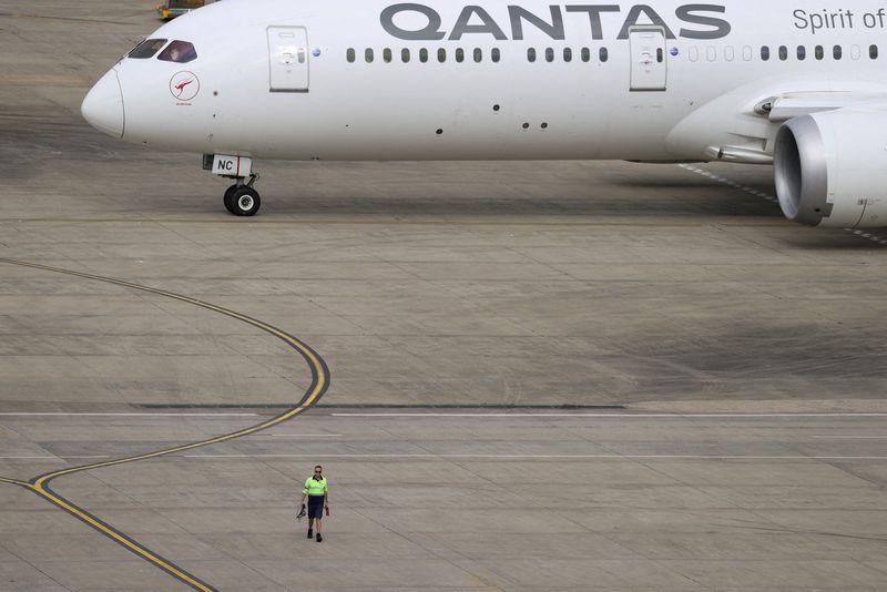 &copy; Reuters. FILE PHOTO: A ground worker walking near a Qantas plane is seen from the international terminal at Sydney Airport in Australia, November 29, 2021.  REUTERS/Loren Elliott/File photo