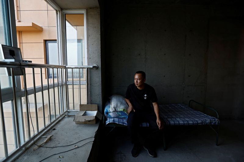 © Reuters. Shi Tieniu, 39, sits on a bed as he poses for a photo at his apartment, in an unfinished residential building at Gaotie Wellness City complex in Tongchuan, Shaanxi province, China September 12, 2023. REUTERS/Tingshu Wang