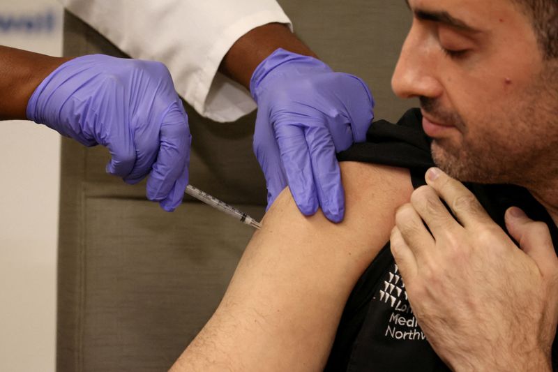 &copy; Reuters. FILE PHOTO: Adam Berman, MD Associate Chair emergency medicine Long Island Jewish Medical Center, who was one of the first Americans to receive the initial COVID vaccine, is inoculated with the updated coronavirus disease (COVID-19) vaccine by Dr. Michell