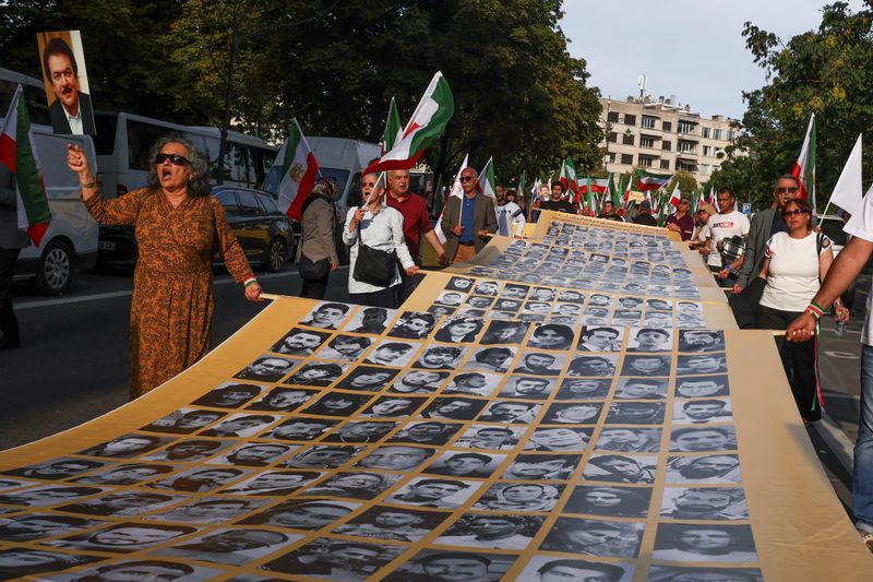 &copy; Reuters. أشخاص يحملون لافتة عليها صور شهداء، كما يطلق عليهم الإيرانيون، خلال مسيرة لإيرانيين في أوروبا، عشية الذكرى السنوية الأولى لوفاة مهسا أميني