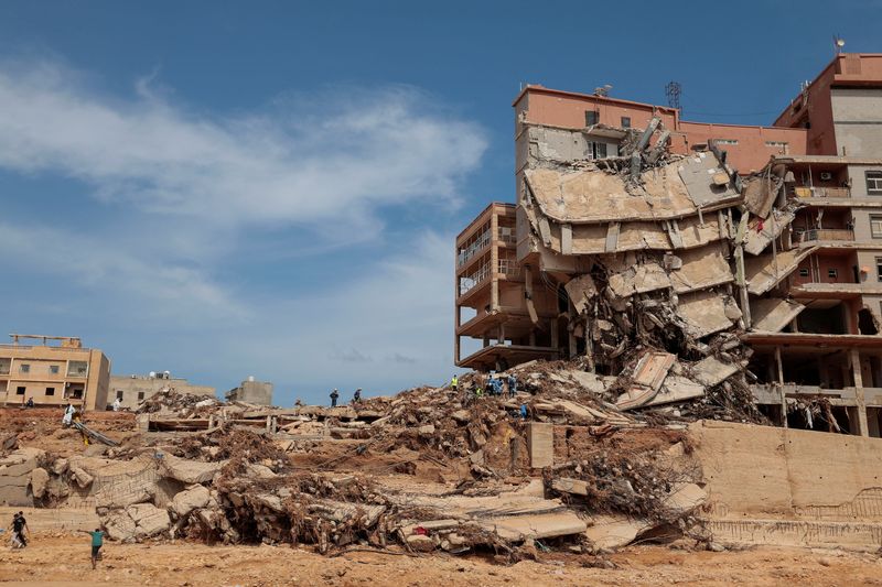 &copy; Reuters. أفراد الإنقاذ يعملون بجوار مبنى مدمر في درنة بشرق ليبيا يوم الأحد عقب الإعصار الذي ضرب المنطقة . تصوير : زهرة بن سمرة - رويترز .  