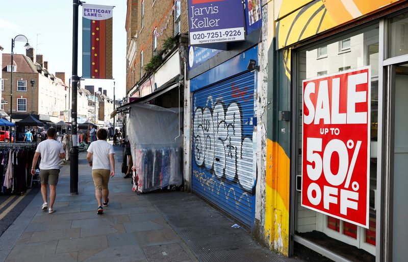 &copy; Reuters. FILE PHOTO: Men walk past a retail unit available to rent and a store offering sale items on Petticoat Lane, in London, Britain, August 23 2023.  REUTERS/Peter Nicholls/File Photo