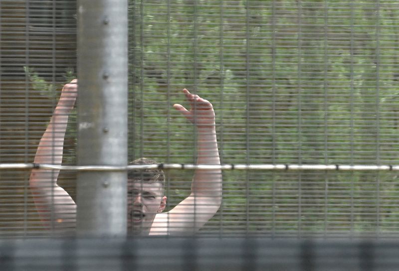 &copy; Reuters. FILE PHOTO: A detainee inside Brook House Immigration Removal Centre gestures as demonstrators protest outside of it against a planned deportation of asylum seekers from Britain to Rwanda, at Gatwick Airport near Crawley, Britain, June 12, 2022. REUTERS/T