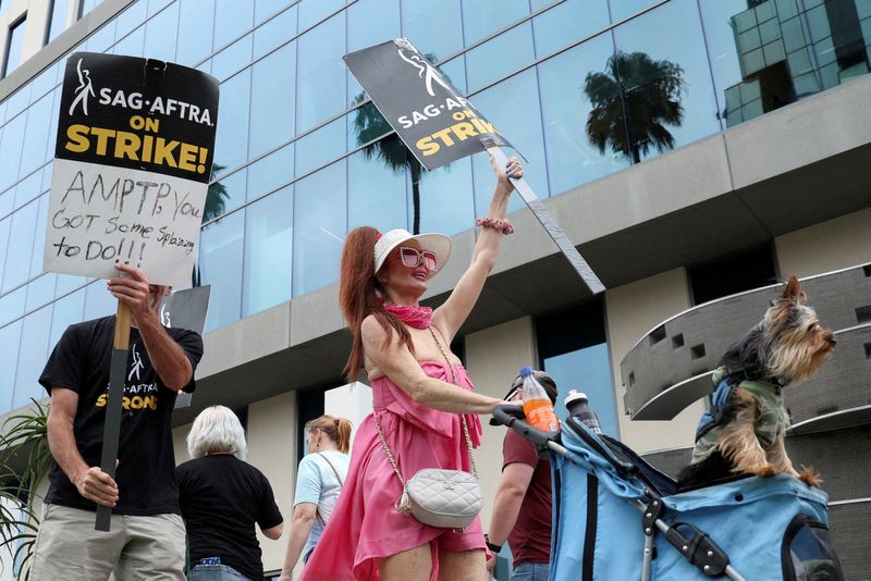 &copy; Reuters. FILE PHOTO: Phoebe Price holds a sign, while pushing a dog in a stroller, as SAG-AFTRA actors and Writers Guild of America (WGA) writers walk the picket line during their ongoing strike outside Sunset Bronson studios, near Netflix offices in Los Angeles, 