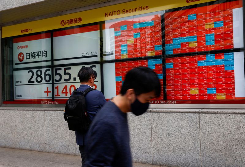 &copy; Reuters. FILE PHOTO: Passersby walk past an electric board displaying Japan's Nikkei share average outside a brokerage in Tokyo, Japan April 18, 2023.  REUTERS/Issei Kato