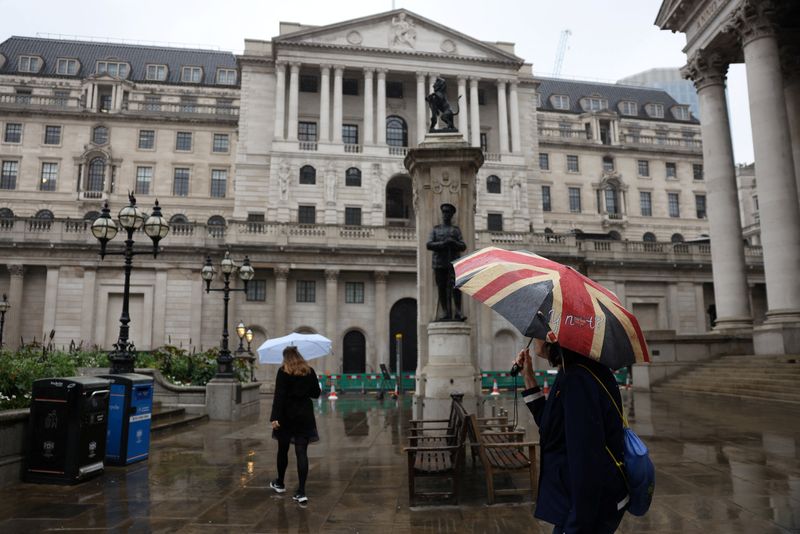 © Reuters. FILE PHOTO: A woman carrying a Union Flag umbrella stands near the Bank of England in the City of London, Britain, July 30, 2023. REUTERS/Hollie Adams/File Photo
