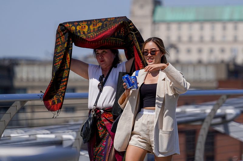 &copy; Reuters. أشخاص يغطون أنفسهم من أشعة الشمس خلال موجة حارة في لندن بصورة من أرشيف رويترز.
