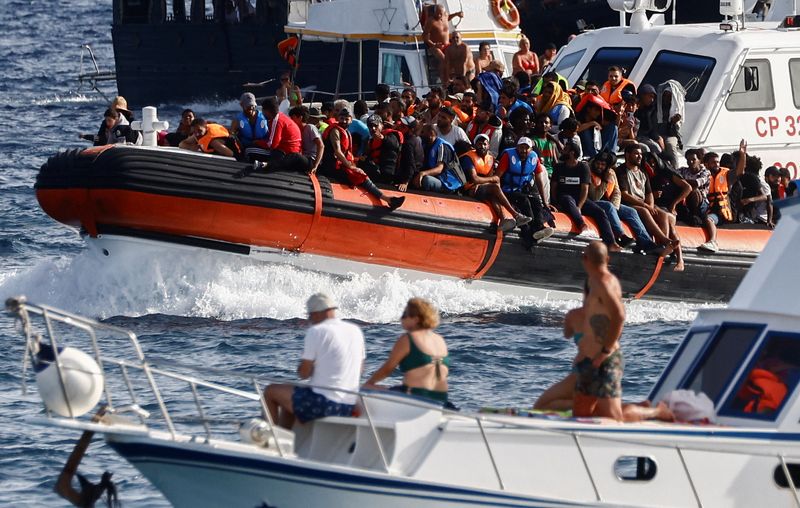 &copy; Reuters. An Italian Coast Guard vessel carrying migrants rescued at sea passes between tourist boats, on the Sicilian island of Lampedusa, Italy, September 18, 2023. REUTERS/Yara Nardi/File Photo