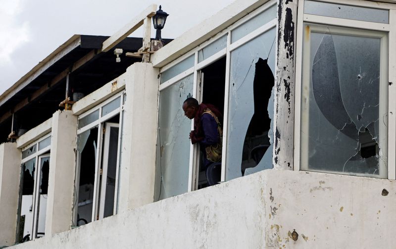 &copy; Reuters. ضابط شرطة صومالي ينظر من نوافذ مكسورة في مطعم عقب هجوم شنه مسلحو حركة الشباب على شاطئ ليدو في مقديشو بالصومال يوم  العاشر من يونيو حزيران 2023. 