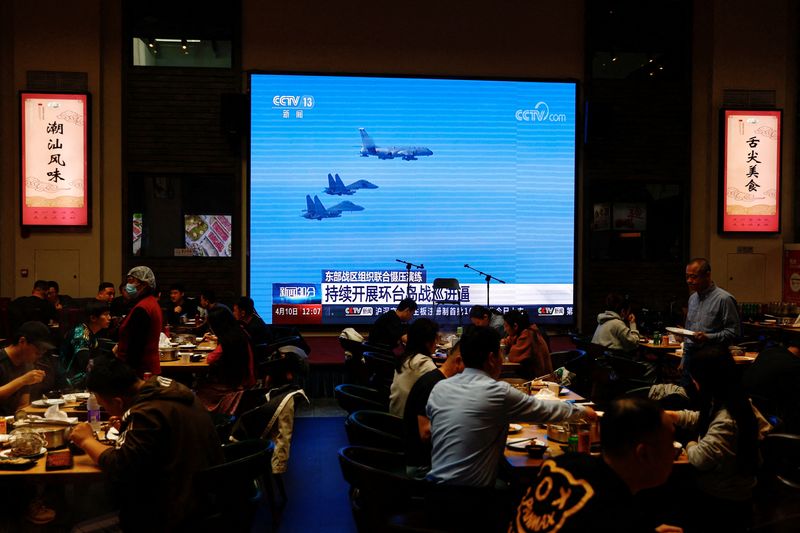 &copy; Reuters. FILE PHOTO: Customers dine near a giant screen broadcasting news footage of aircraft of the Air Force under the Eastern Theatre Command of China's People's Liberation Army (PLA) taking part in a combat readiness patrol and "Joint Sword" exercises around T