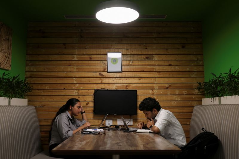 &copy; Reuters. FILE PHOTO: People sit and work on their laptops at Deloitte's office in Gurugram, India, June 13, 2023. REUTERS/Anushree Fadnavis/File Photo