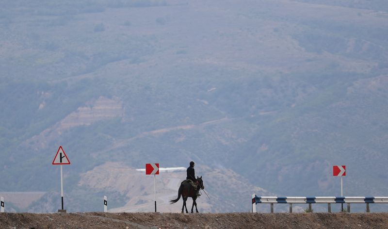 © Reuters. A man rides a horse along a road near the Armenia-Azerbaijan border outside the village of Kornidzor, Armenia, September 23, 2023. REUTERS/Irakli Gedenidze