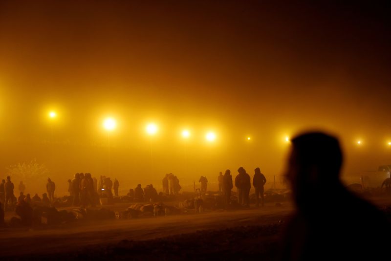© Reuters. FILE PHOTO: Migrants stand near the border wall during a sandstorm after having crossed the U.S.-Mexico border to turn themselves in to U.S. Border Patrol agents, as the U.S. prepares to lift COVID-19 era Title 42 restrictions that have blocked migrants at the border from seeking asylum since 2020, in El Paso, Texas, U.S., May 10, 2023. REUTERS/Jose Luis Gonzalez/File Photo