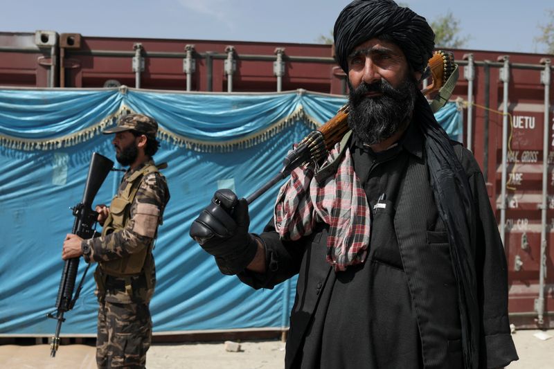 &copy; Reuters. FILE PHOTO: Taliban fighters stand guard while people wait to receive sacks of rice, as part of humanitarian aid sent by China, at a distribution centre in Kabul, Afghanistan, April 7, 2022. REUTERS/Ali Khara/File Photo