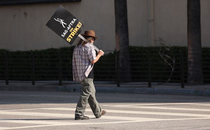 © Reuters. A person holding a sign walks outside Warner Bros. Studios the day after the Writers Guild of America (WGA) announced it reached a preliminary labor agreement with major studios in Burbank, California, U.S., September 25, 2023. REUTERS/Mario Anzuoni