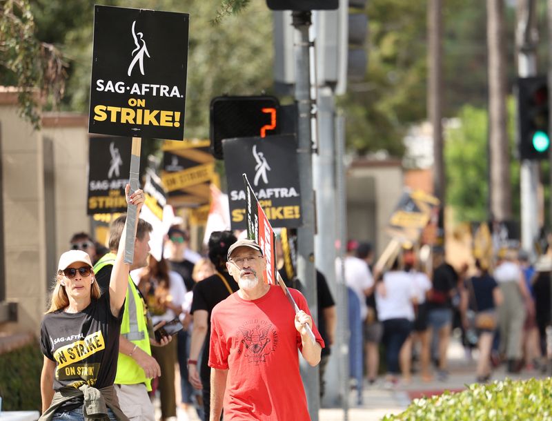 © Reuters. FILE PHOTO: SAG-AFTRA actors and Writers Guild of America (WGA) writers walk the picket line during their ongoing strike outside Warner Bros. Studio in Burbank, California, U.S., September 6, 2023. REUTERS/Mario Anzuoni/File photo