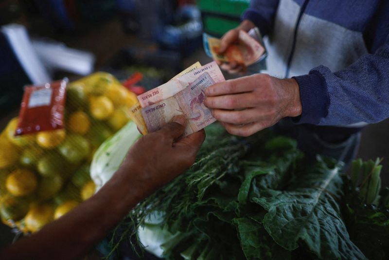 © Reuters. FILE PHOTO: A man pays a vendor at a fruit stand, at a supply centre (CEASA) in Brasilia, Brazil May 9, 2023. REUTERS/Adriano Machado/File Photo