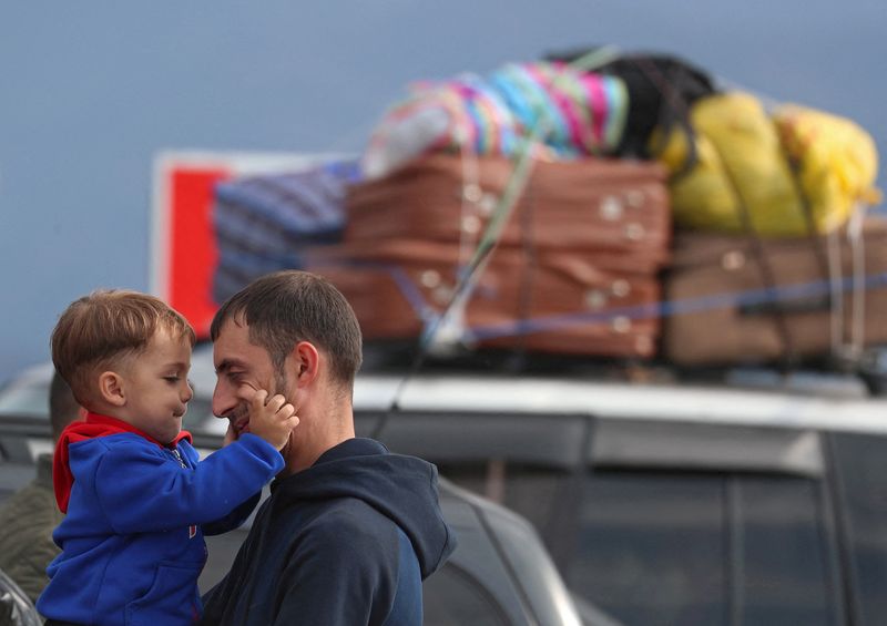 &copy; Reuters. A refugee from Nagorno-Karabakh region holds a child while standing next to a car upon their arrival in the border village of Kornidzor, Armenia, September 26, 2023. REUTERS/Irakli Gedenidze