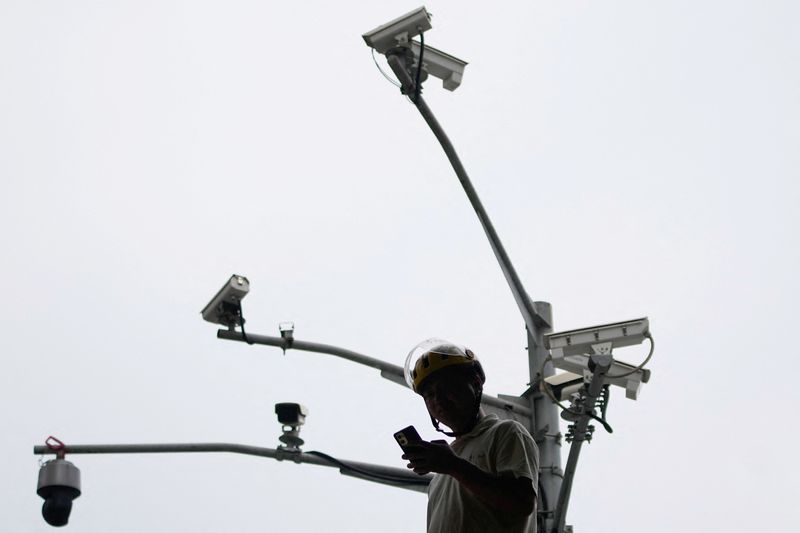 © Reuters. A man looks at a phone under surveillance cameras on a street, in Shanghai, China September 27, 2023. REUTERS/Aly Song