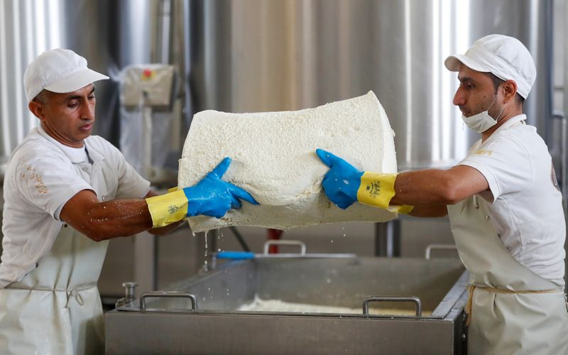 &copy; Reuters. FILE PHOTO: Workers holding a piece of curd in a factory producing a hard and salty cheese called Pecorino Romano, a product which may be hit by U.S. tariffs, in Fiano Romano outside Rome, Italy, October 14, 2019. Picture taken October 14, 2019. REUTERS/Y
