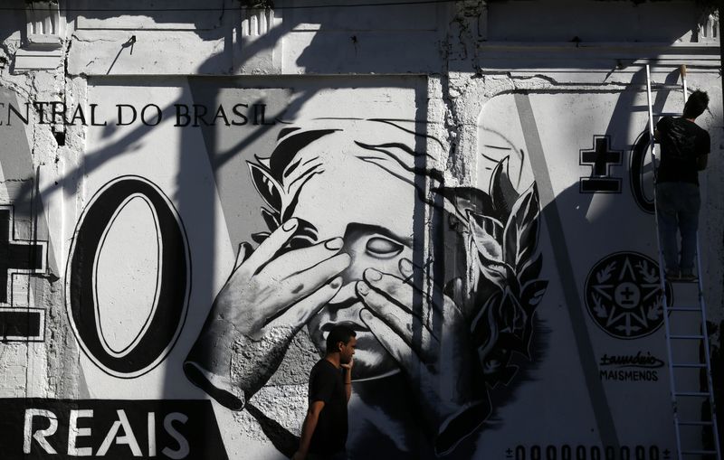 &copy; Reuters. Pessoa passa em frente a grafite retratando uma nota de real estilizada no centro do Rio de Janeiro
31/07/2014
REUTERS/Pilar Olivares