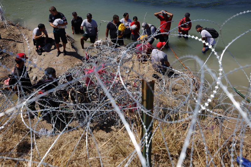 &copy; Reuters. Migrants wait behind razor wire after crossing the Rio Grande into the United States in Eagle Pass, Texas, U.S., September 28, 2023.   REUTERS/Brian Snyder