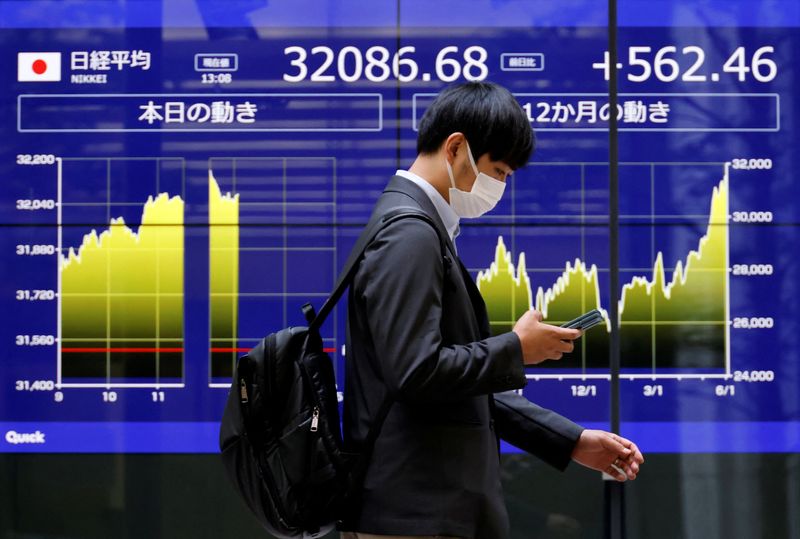 &copy; Reuters. FILE PHOTO: A man walks past an electric monitor displaying Japan's Nikkei share average and recent movements, outside a bank in Tokyo, Japan, June 5, 2023. REUTERS/Issei Kato/File Photo