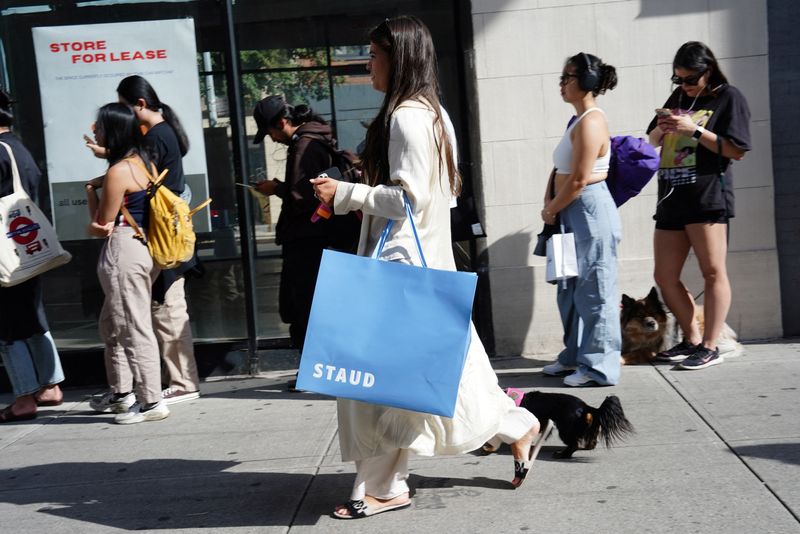 &copy; Reuters. A woman carrying a shopping bag from Staud walks past people queuing for a pop-up shop in the SoHo neighborhood of New York City, U.S., September 21, 2023.  REUTERS/Bing Guan