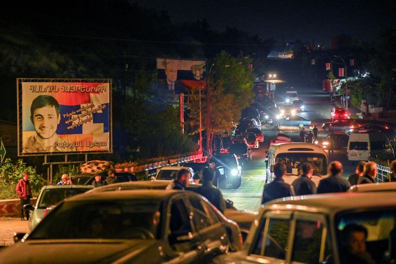 &copy; Reuters. Residents in vehicles attempt to leave the city of Stepanakert following a military operation conducted by Azerbaijani armed forces in Nagorno-Karabakh, a region inhabited by ethnic Armenians, September 24, 2023. A board in the background displays a Russi