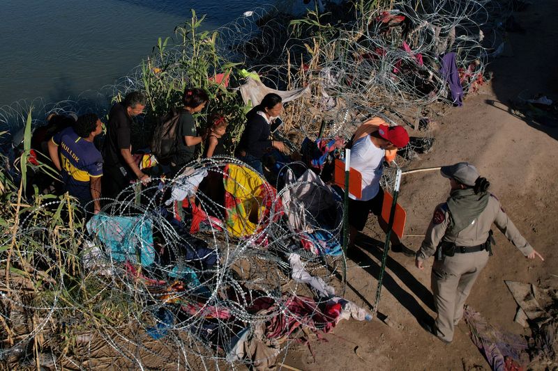 © Reuters. Authorities let migrants through the razor wire after crossing the Rio Grande in Eagle Pass, Texas, U.S., September 29, 2023.   REUTERS/Brian Snyder
