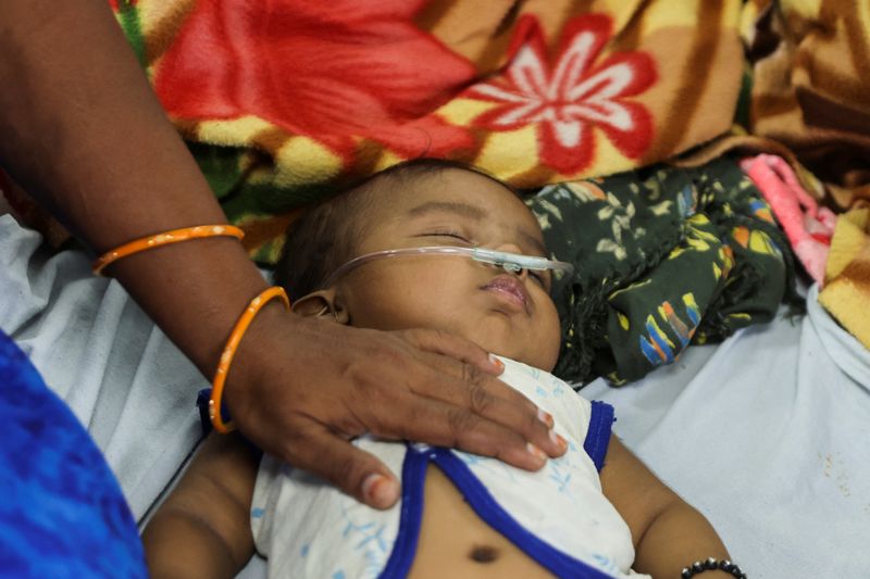 &copy; Reuters. أم تحمل ابنها الذي تم تشخيص إصابته بالالتهاب الرئوي داخل جناح الأطفال بكلية ومستشفى شانكاراو تشافان الطبي الحكومي في نانديد بالهند يوم الث