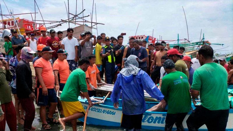 © Reuters. Philippine Coast Guard personnel pictured on October 3, 2023, retrieve the body of a fisherman on the coast of Infanta, Pangasinan Province, Philippines, after a deadly collision incident in the South China Sea, in this handout image released by the Philippine Coast Guard on October 4, 2023. Philippine Coast Guard/Handout via REUTERS   