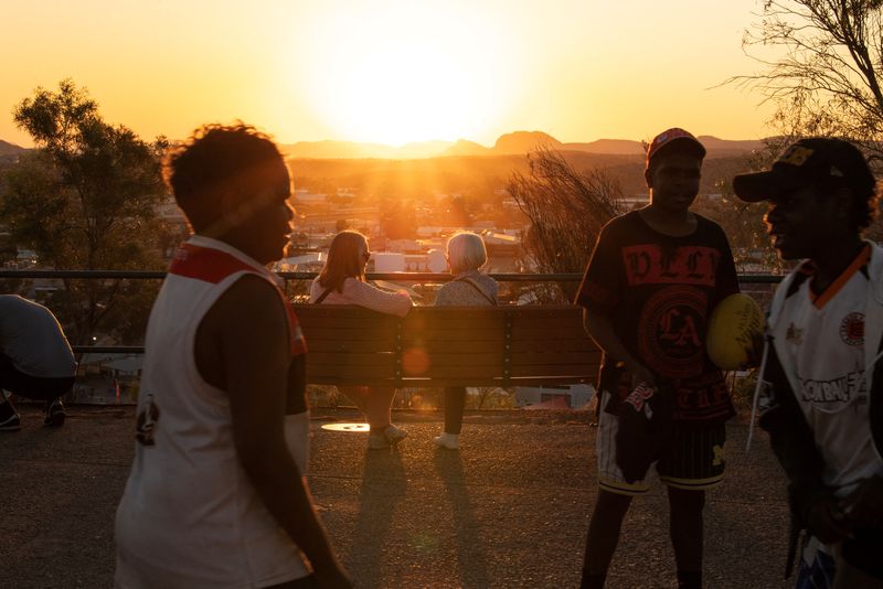 © Reuters. Boys play as people watch the sunset over the township of Alice Springs, ahead of a nationwide referendum on Indigenous issues, in Australia, September 14, 2023. On October 14, Australians will vote on whether to recognise Aboriginal and Torres Strait Islander people in the constitution and enshrine in it an advisory body called the Voice to Parliament that would give non-binding advice to lawmakers on matters concerning the continent's first inhabitants. Unlike New Zealand, Canada and the U.S., Australia has no treaty with its Indigenous people, who make up about 3.8 per cent of the population. Under government policies they suffered dispossession of their homelands and forced separation of children from their parents until well into the 20th century. Many live in poverty and experience lower life expectancy, high incarceration rates and poor educational outcomes.     REUTERS/Jaimi Joy 