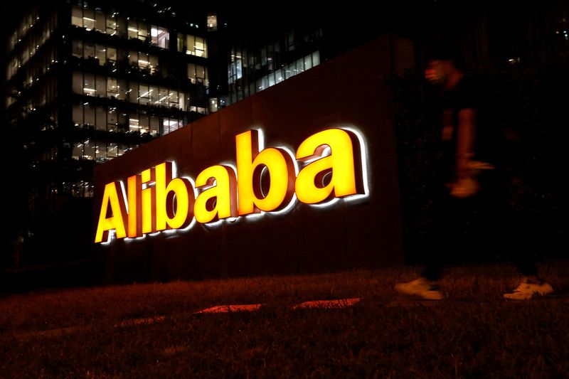 &copy; Reuters. FILE PHOTO: A man walks past a logo of Alibaba Group at its office building in Beijing, China August 9, 2021. REUTERS/Tingshu Wang//File Photo