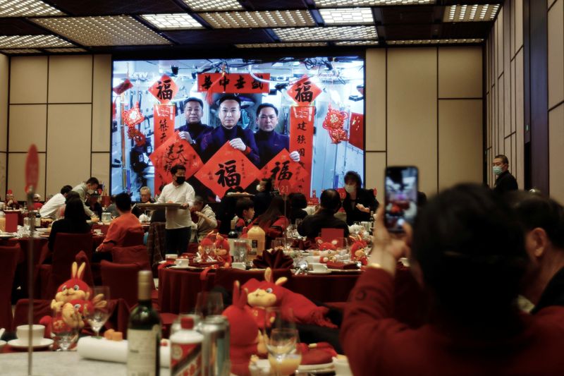 &copy; Reuters. FILE PHOTO:A woman takes pictures of a screen displaying the Spring Festival greetings by Chinese astronauts Fei Junlong, Deng Qingming and Zhang Lu from China's space station, during a Lunar New Year's Eve dinner service at Shangri-La Shougang Park hotel