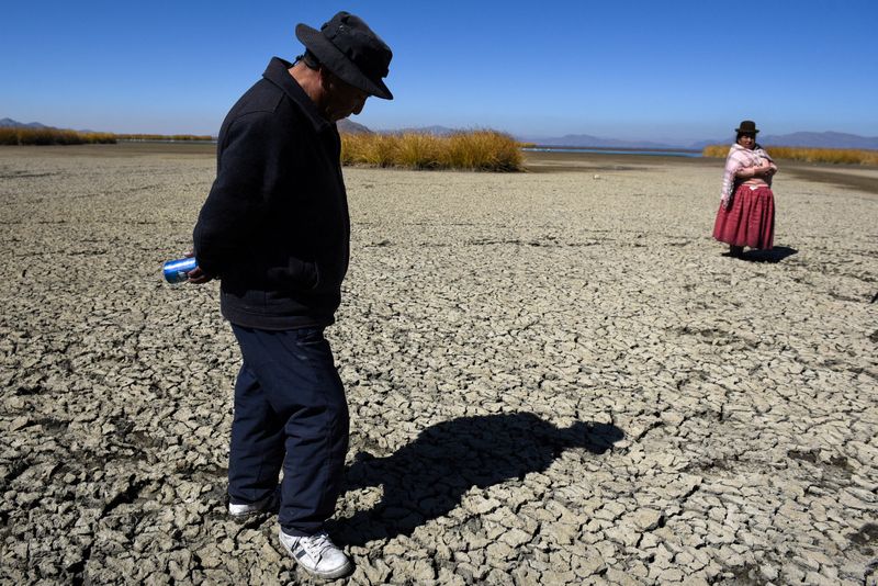 &copy; Reuters. FOTO DE ARCHIVO: Gabriel Flores e Isabel Apaza caminan sobre el lecho seco y agrietado cerca de la orilla del lago Titicaca en época de sequía en Huarina, Bolivia 3 de agosto de 2023. REUTERS/Claudia Morales/File Photo/File Photo 