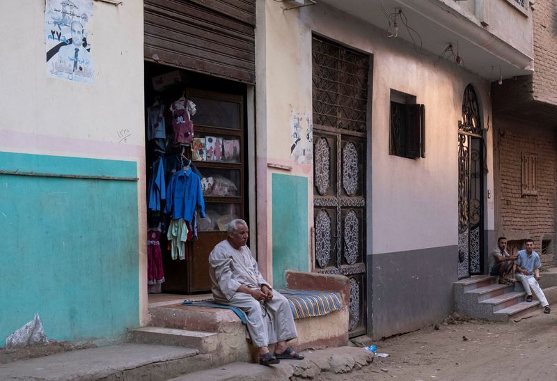 &copy; Reuters. Un uomo siede davanti al suo negozio in attesa di clienti nel villaggio di Mit Suhayl, la città natale di alcuni migranti egiziani morti dopo che un'imbarcazione si è rovesciata vicino alle coste della Grecia a giugno, governatorato di Sharqia, Egitto, 