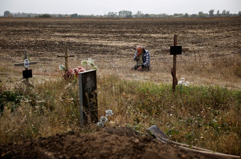 © Reuters. Valeriy Kozyr, 61, cries as he sits next to graves after losing his daughter and other relatives in a Russian military strike, amid Russia's attack on Ukraine, at a cemetery outside the village of Hroza, Kharkiv region, Ukraine October 6, 2023. REUTERS/Thomas Peter    