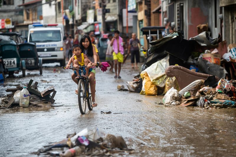 &copy; Reuters. Crianças em bicicleta passam por destroços deixados pela enchente causada pelo tufão Noru, na Cidade de Marikina, nas Filipinas
26/09/2022 REUTERS/Lisa Marie David