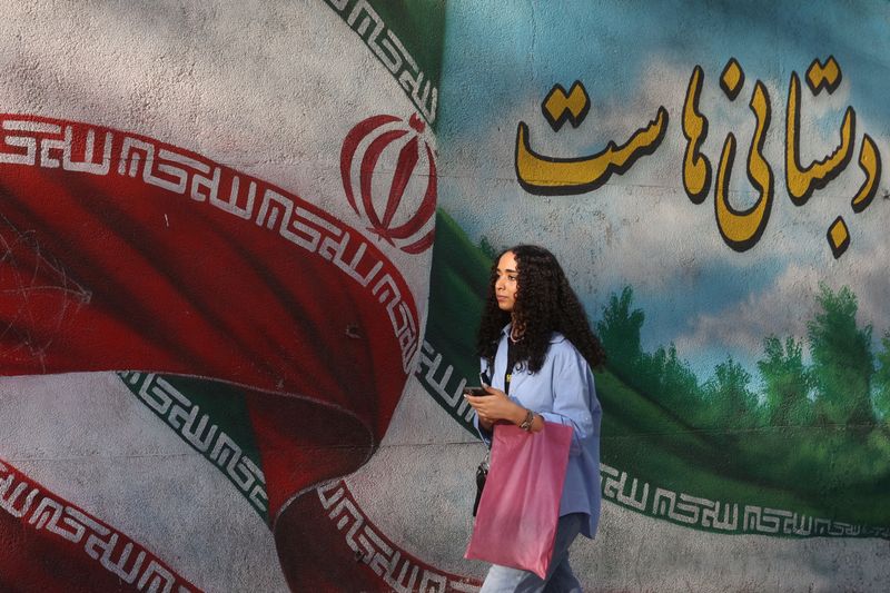 &copy; Reuters. امرأة إيرانية تمشي أمام لوحة جدارية عليها صورة العلم الإيراني في أحد شوارع طهران يوم الجمعة. صورة لرويترز من وكالة أنباء غرب آسيا.