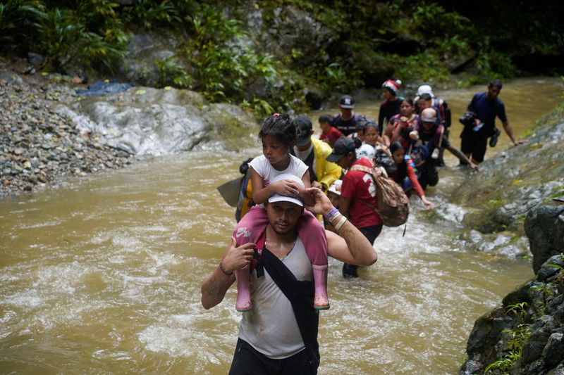 &copy; Reuters. FILE PHOTO: A migrant carries a child as they along with others continue their journey to the U.S. border, in Acandi, Colombia July 9, 2023. REUTERS/Adri Salido/File Photo