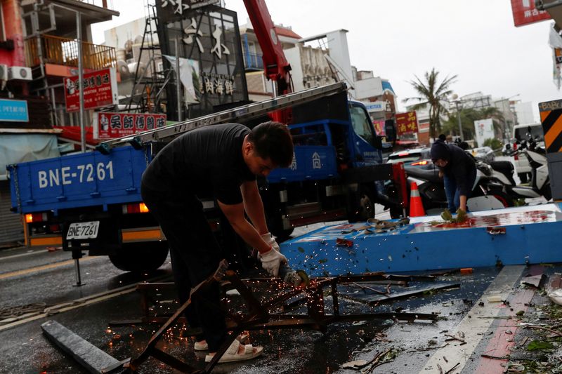 &copy; Reuters. عامل يقطع الهيكل المعدني للافتة متساقطة عقب إعصار كوينو بتايوان يوم الخميس. تصوير: كارلوس جارسيا رولينز - رويترز.