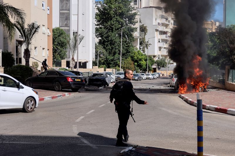 &copy; Reuters. شرطي إسرائيلي يسير نحو حريق بعد إطلاق صواريخ من قطاع غزة في عسقلان يوم السبت. تصوير: سنان أبو مايزر - رويترز